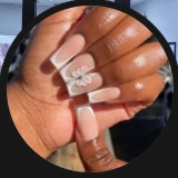 Close-up of pink and white acrylic nails with a white bow accent.